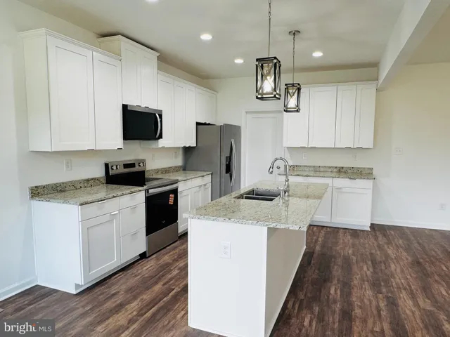 a kitchen with a sink a microwave a refrigerator and cabinets