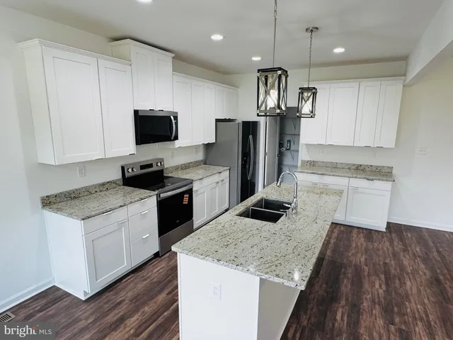 a kitchen with stainless steel appliances granite countertop a sink stove a refrigerator and a oven with wooden floor