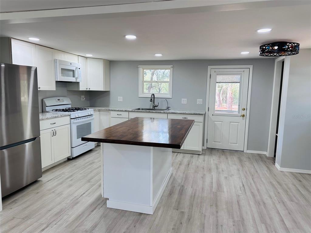13750 Northwest 88th Terrace Chiefland, FL 32626 - Photo 8 of 33 a kitchen with wooden floors and refrigerator