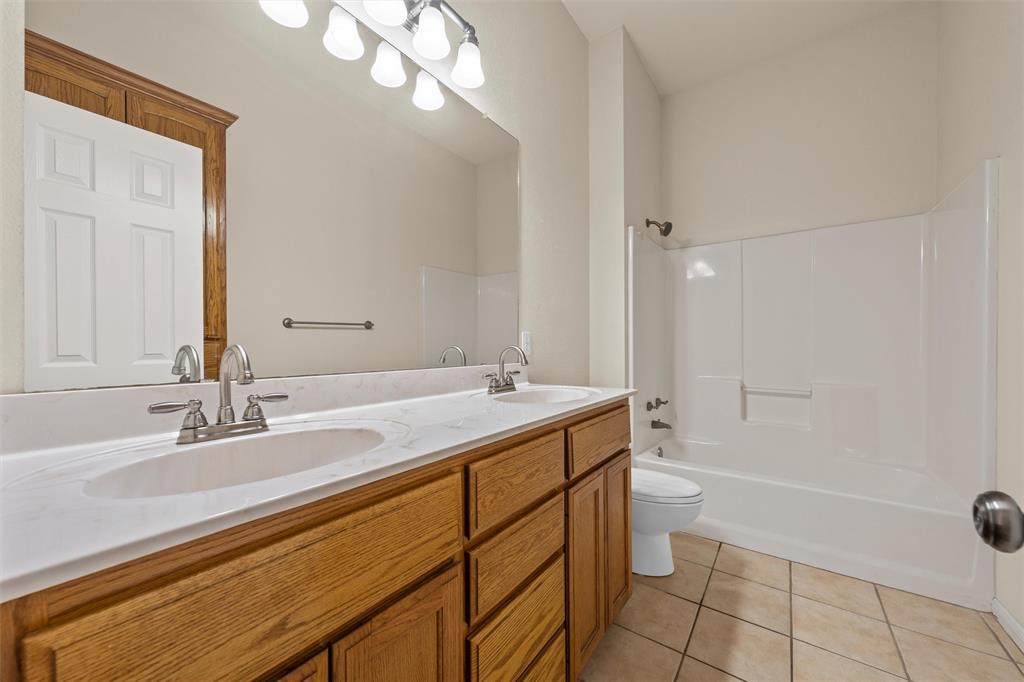 940 Cheyenne Trail Hewitt, TX 76643 - Photo 22 of 40 Full bath with double vanity, light tile patterned floors, and washtub / shower combination