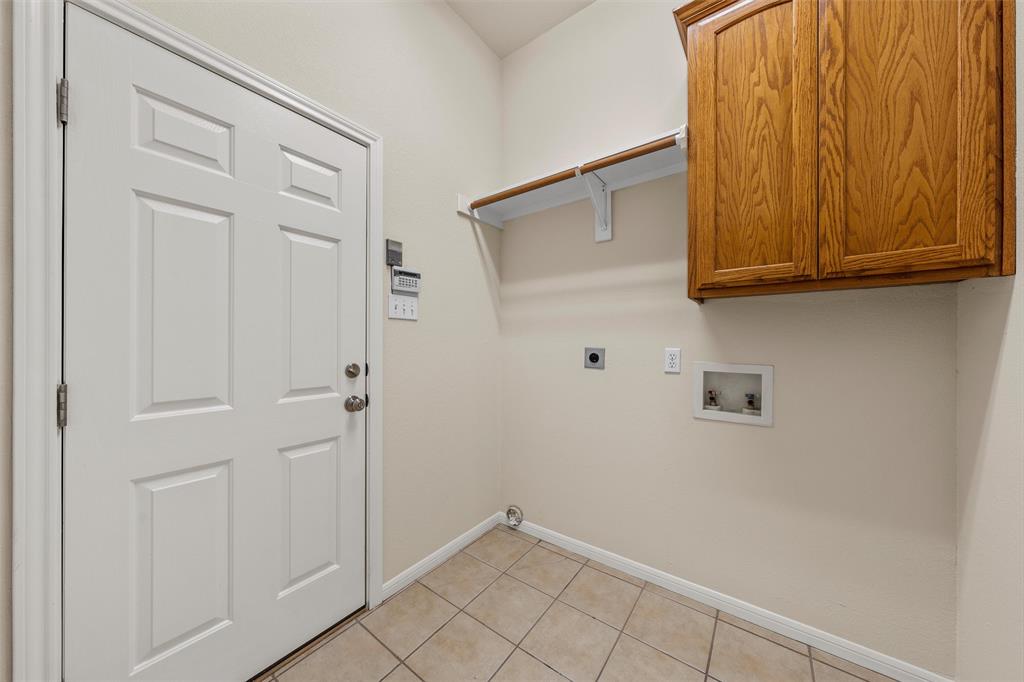 940 Cheyenne Trail Hewitt, TX 76643 - Photo 25 of 40 Laundry room with hookup for an electric dryer, light tile patterned floors, washer hookup, and cabinet space