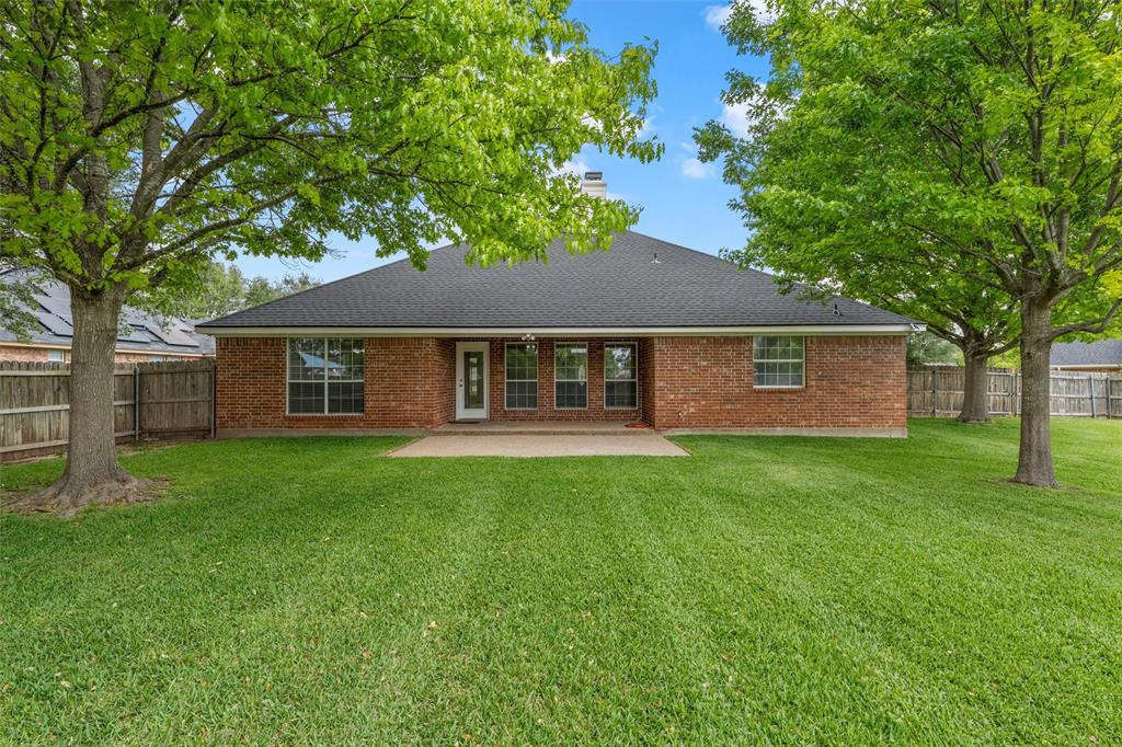940 Cheyenne Trail Hewitt, TX 76643 - Photo 29 of 40 Back of property featuring a chimney, a patio, a fenced backyard, brick siding, and a shingled roof