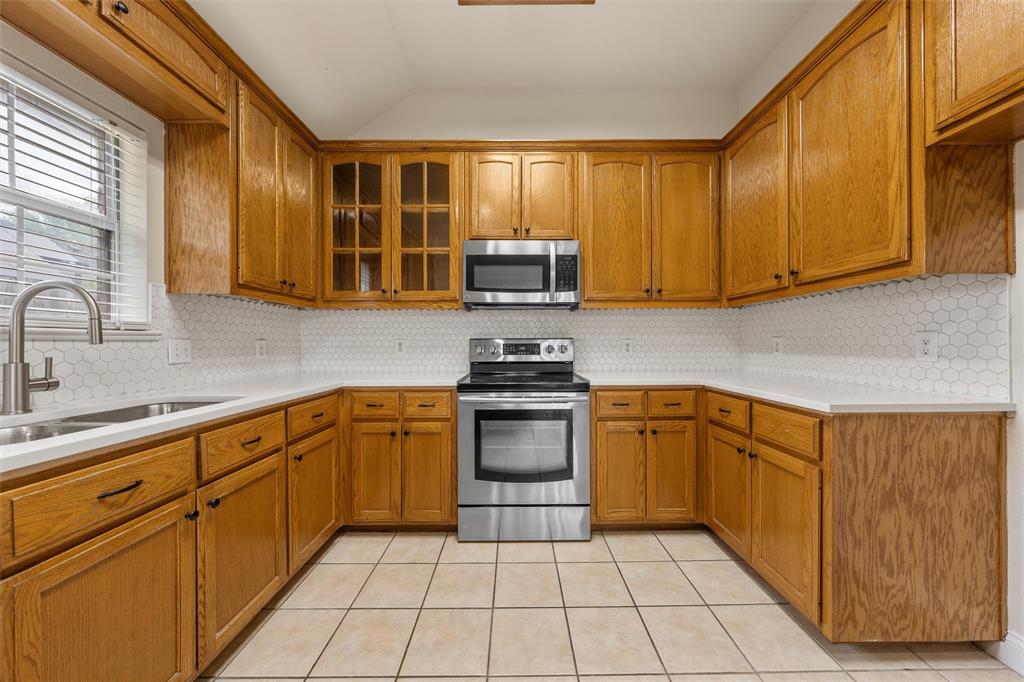 940 Cheyenne Trail Hewitt, TX 76643 - Photo 8 of 40 Kitchen featuring stainless steel appliances, wood finish cabinets, light tile patterned floors, tasteful backsplash, and vaulted ceiling