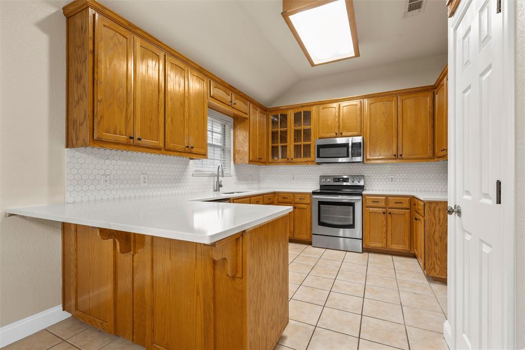 940 Cheyenne Trail Hewitt, TX 76643 - Photo 10 of 40 Kitchen with a peninsula, light tile patterned floors, stainless steel appliances, lofted ceiling, and light countertops