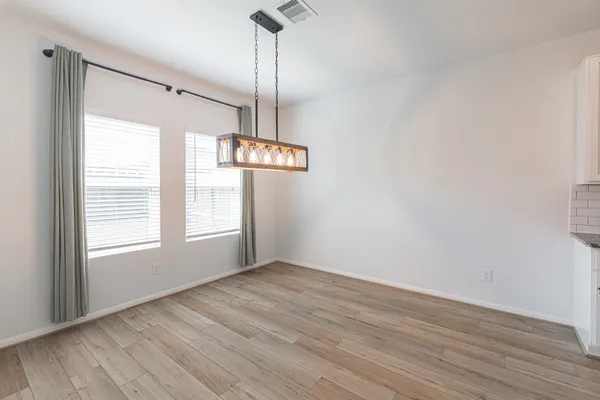 a kitchen with stainless steel appliances granite countertop a refrigerator a stove top oven a sink dishwasher and a dining table with wooden floor