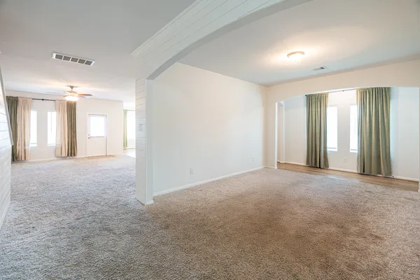 a view of a big room with windows and chandelier fan