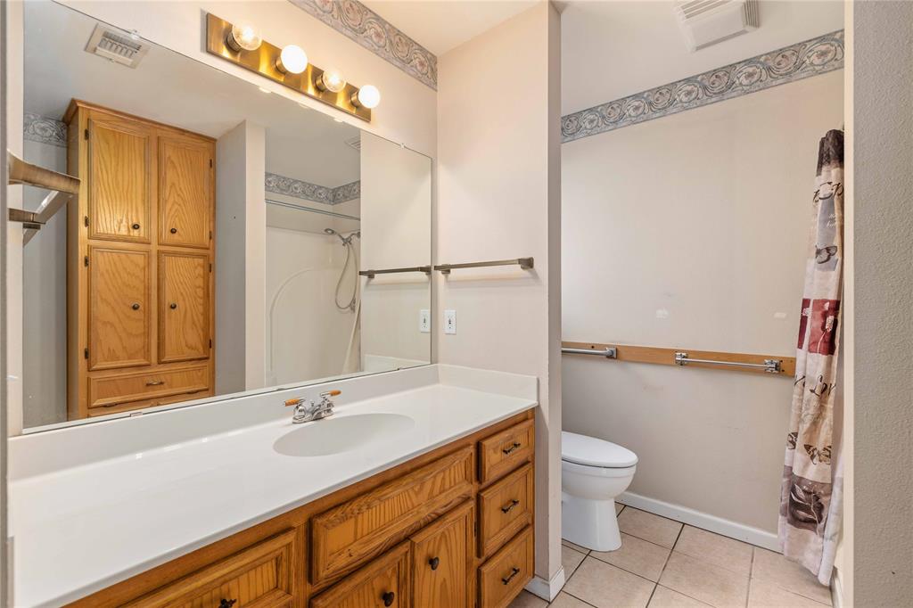4300 County Road 372 Early, TX 76802 - Photo 20 of 40 a bathroom with a sink a toilet a mirror and shower