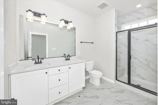 a bathroom with a double vanity sink toilet and shower