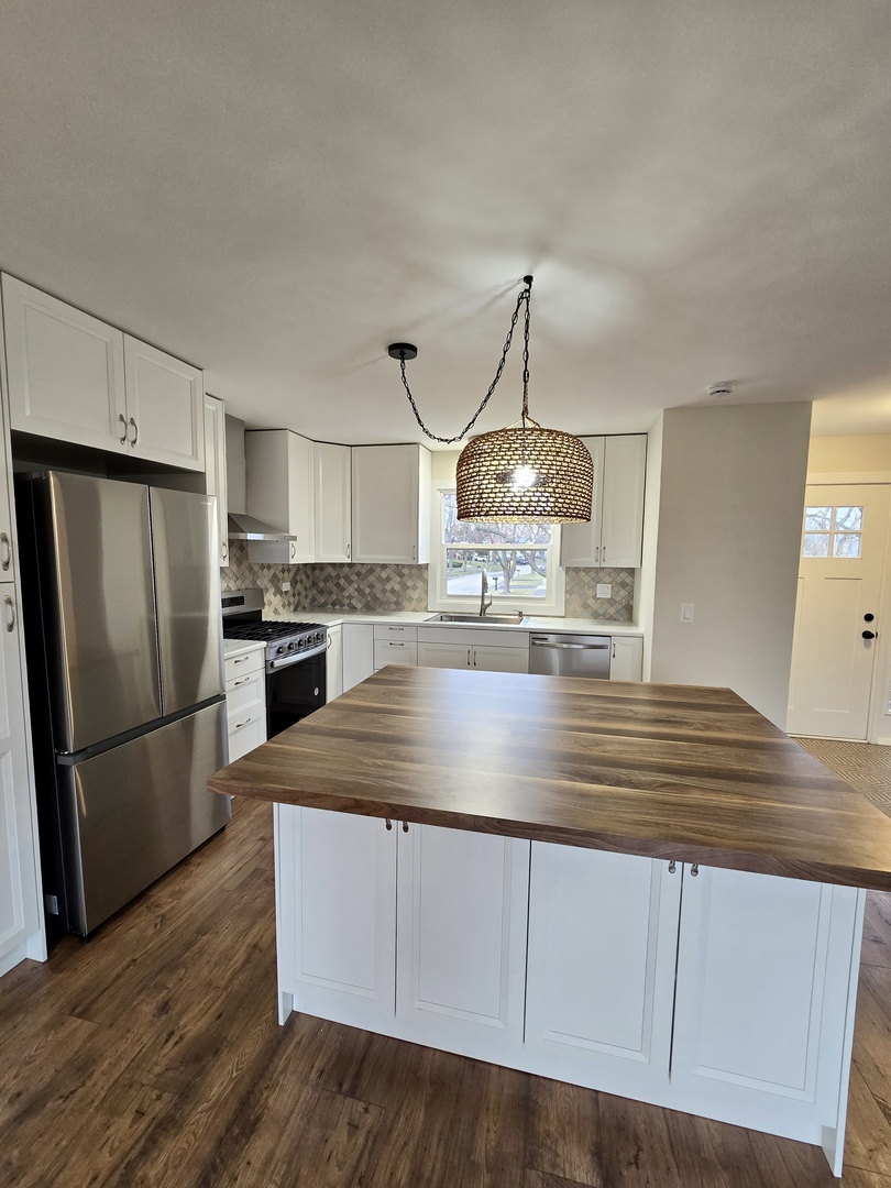 1010 Ridgewood Drive Bolingbrook, IL 60440 - Photo 5 of 29 a kitchen with kitchen island white cabinets a refrigerator and a sink