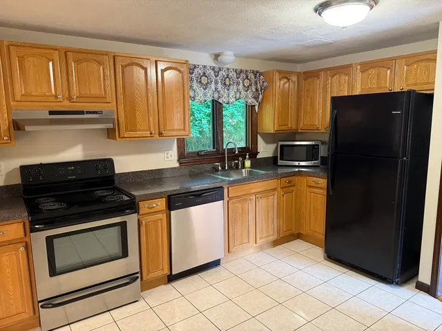 a kitchen with granite countertop a refrigerator stove and sink