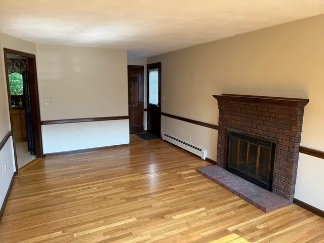 a view of a livingroom with wooden floor and a fireplace