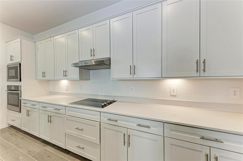 13021 Tulum Loop Venice, FL 34293 - Photo 8 of 66 a kitchen with granite countertop white cabinets and stainless steel appliances
