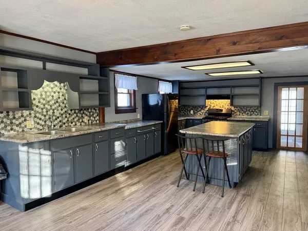 a kitchen with stainless steel appliances granite countertop a sink a stove and a wooden floors