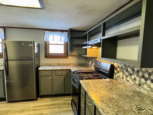 a kitchen with stainless steel appliances granite countertop a refrigerator and a stove top oven
