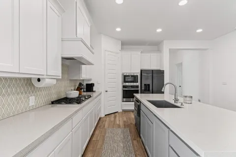 a kitchen with kitchen island a sink appliances and cabinets
