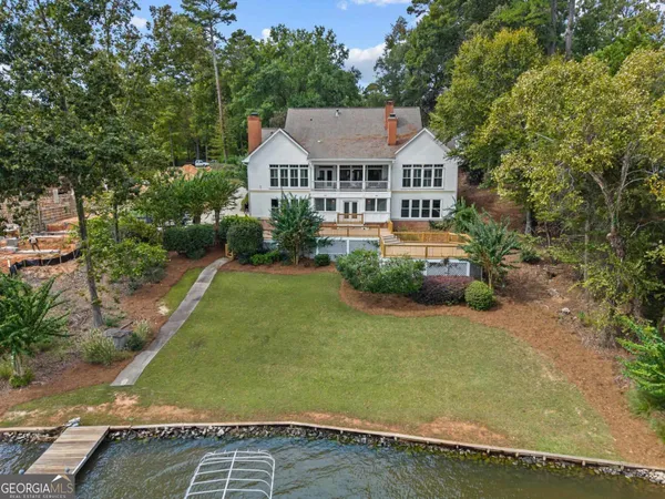 an aerial view of ocean with residential house with outdoor space and trees all around