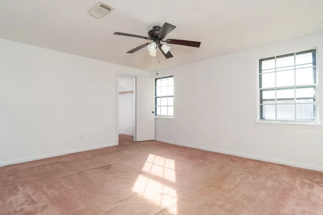 an empty room with windows and fan
