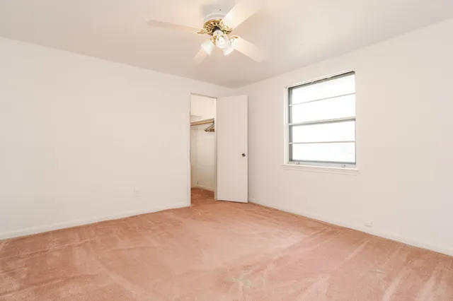 an empty room with windows and fan