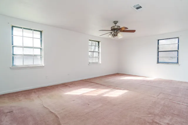 an empty room with windows and fan
