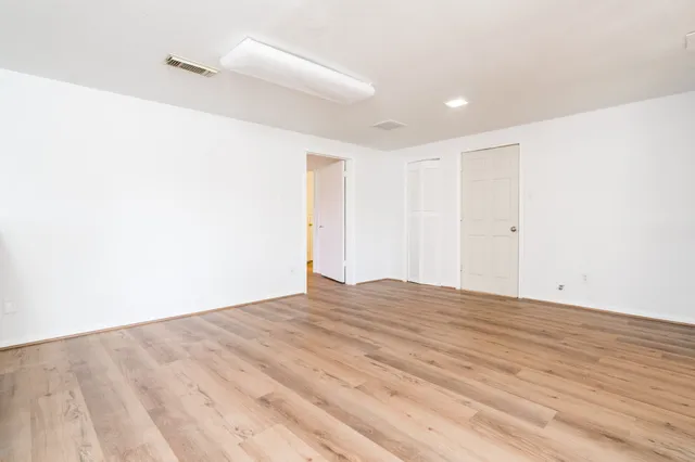 a view of empty room with wooden floor and fan