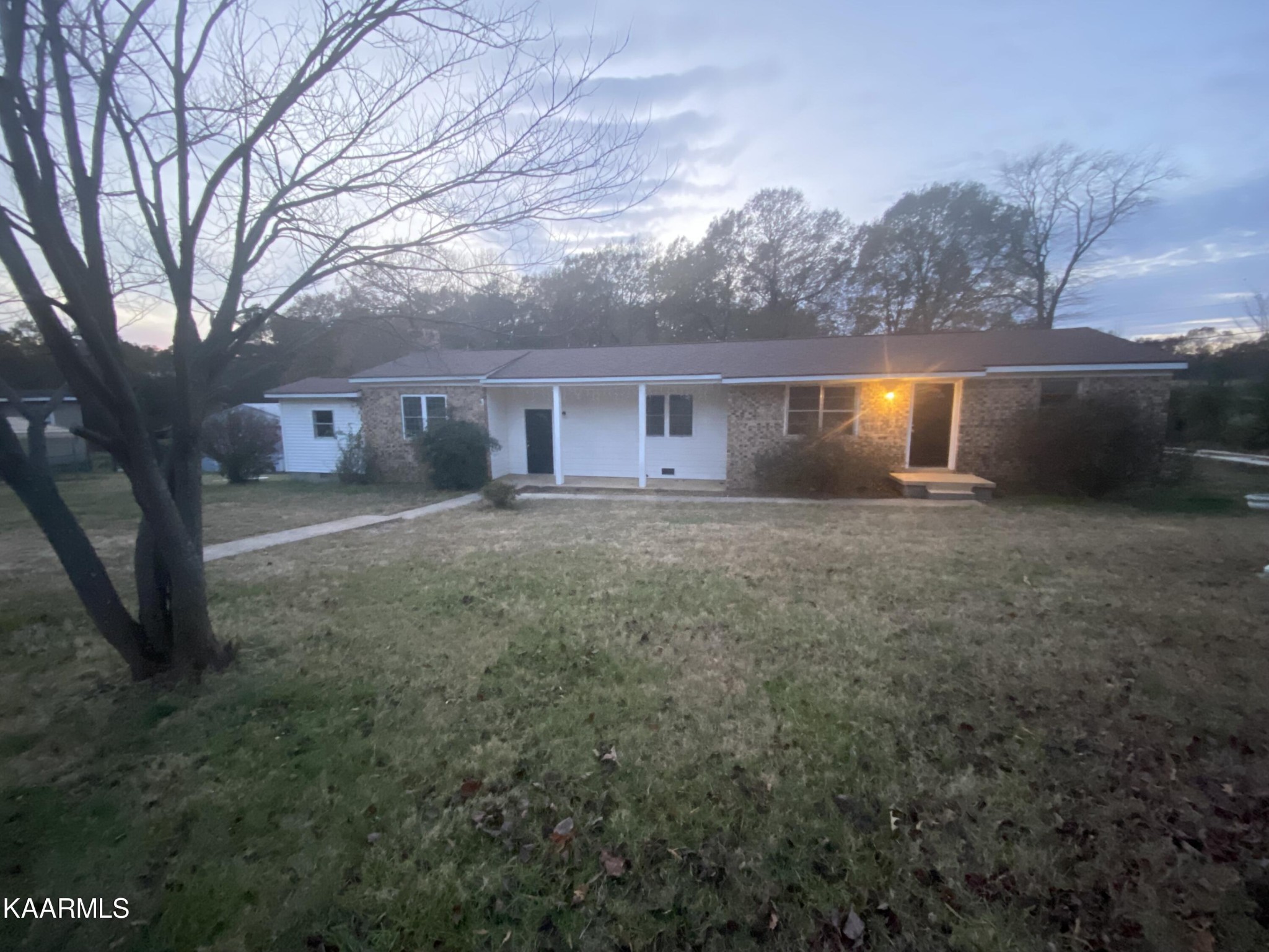 front view of house with yard and trees in the background