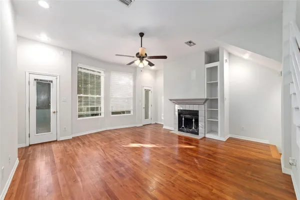 a view of an empty room with wooden floor fireplace and a window