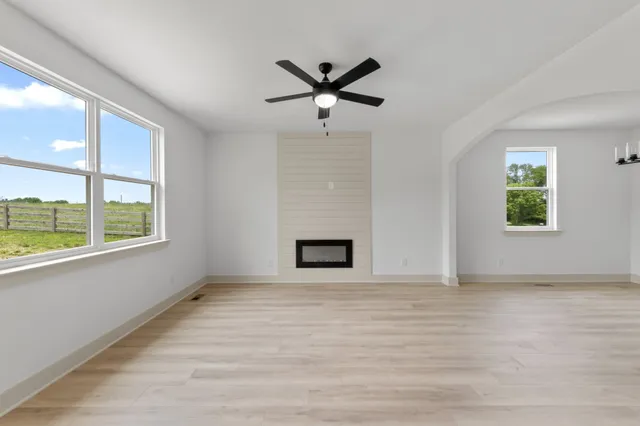 an empty room with windows and ceiling fan