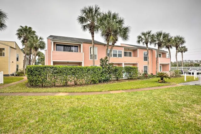 a view of a house with a big yard and palm trees