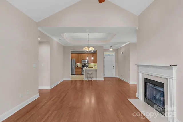 a view of an empty room with wooden floor fireplace and a window