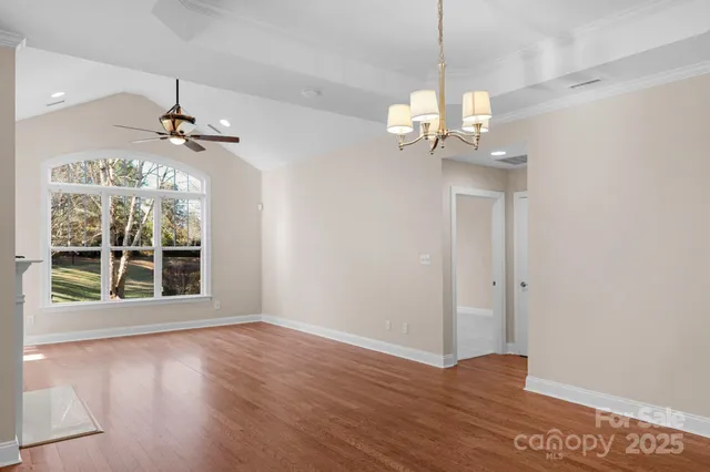 a view of a room with wooden floor chandelier and windows