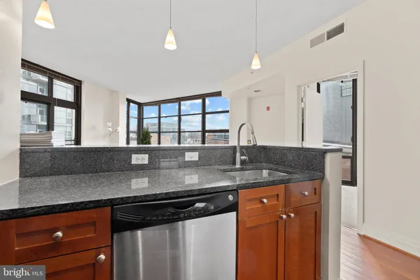 a kitchen with stainless steel appliances granite countertop a sink a stove and a wooden cabinets