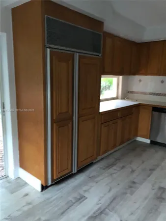 a kitchen with granite countertop wooden cabinets and a refrigerator