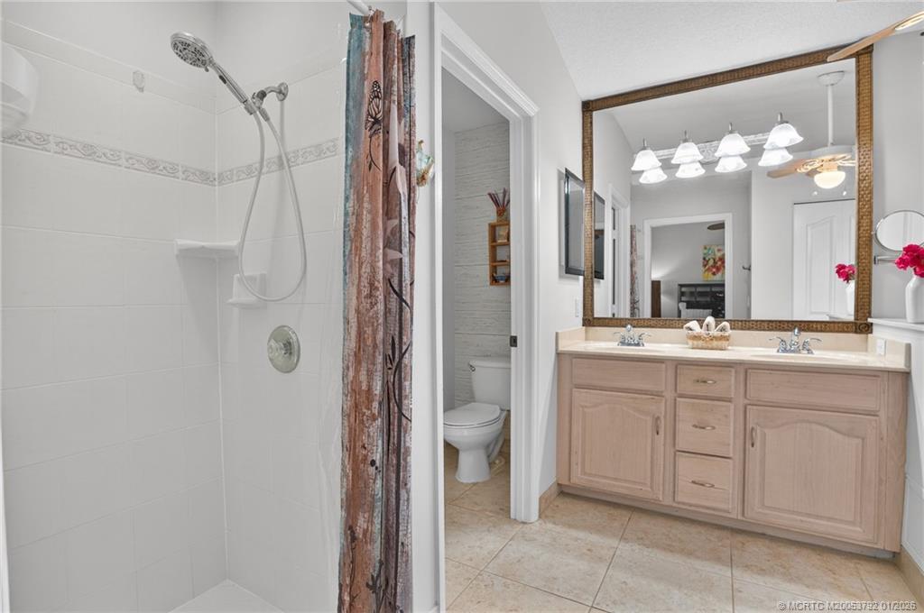9275 Southeast Mercury Street Hobe Sound, FL 33455 - Photo 11 of 65 a bathroom with a granite countertop sink a toilet and a mirror