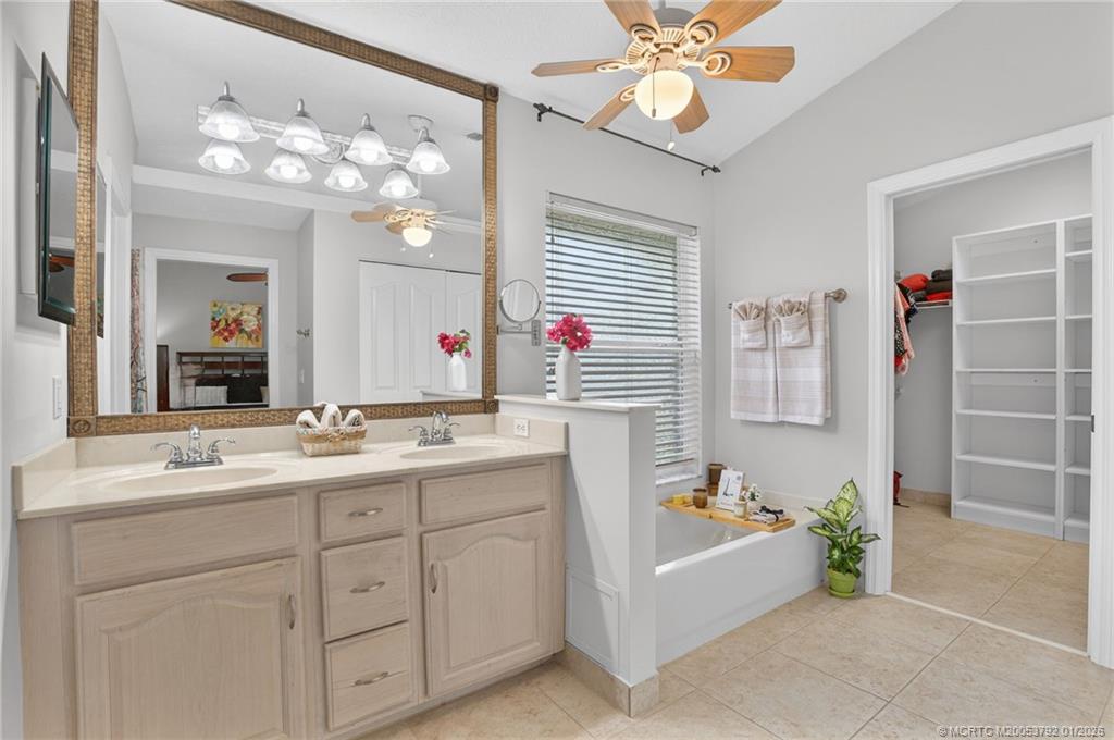9275 Southeast Mercury Street Hobe Sound, FL 33455 - Photo 12 of 65 a bathroom with a sink a vanity a mirror a bathtub and a shower