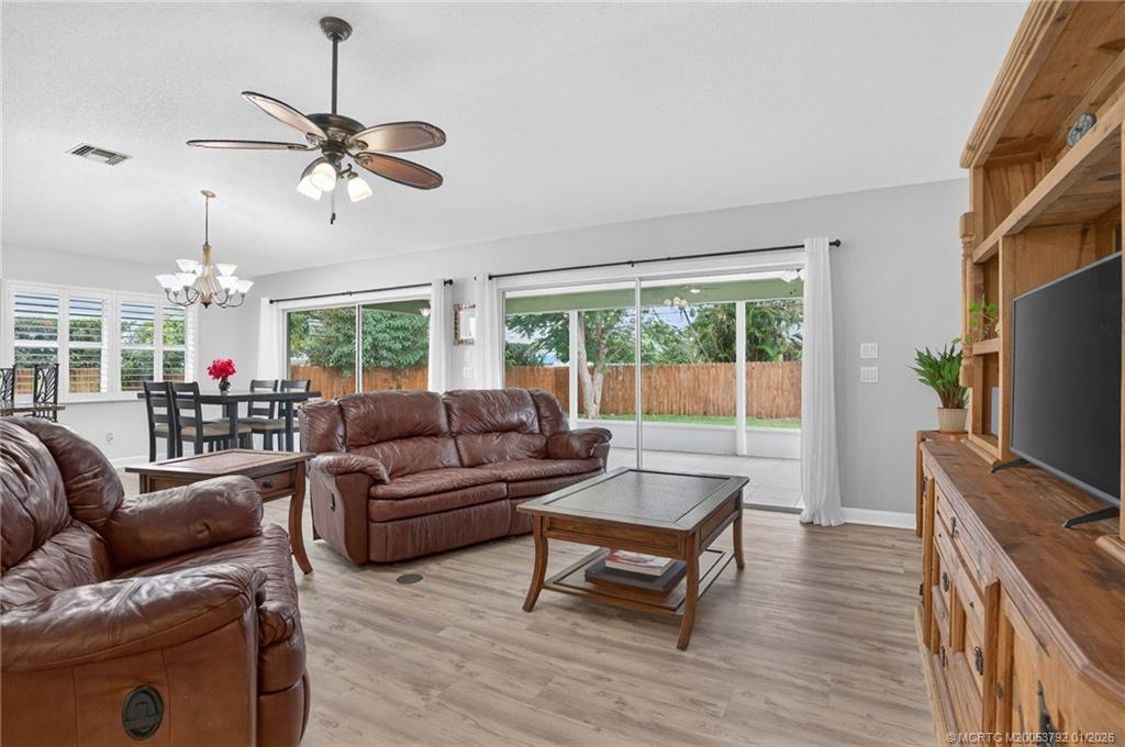 9275 Southeast Mercury Street Hobe Sound, FL 33455 - Photo 18 of 65 a living room with furniture a ceiling fan and a flat screen tv