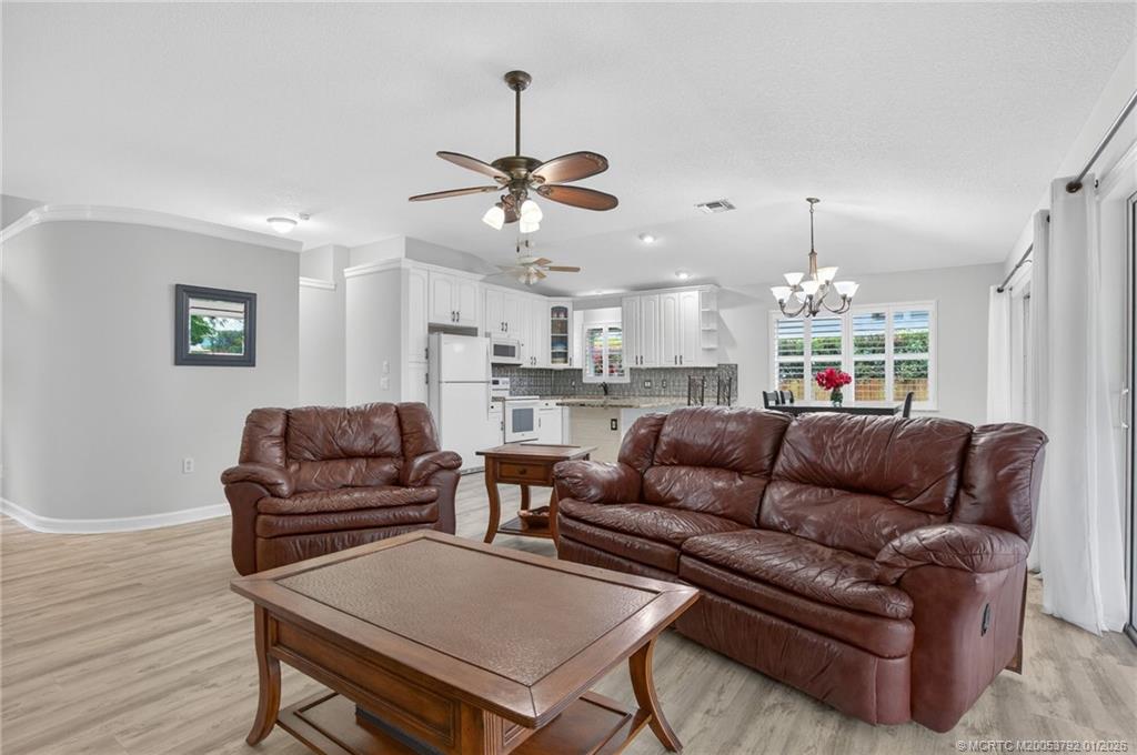 9275 Southeast Mercury Street Hobe Sound, FL 33455 - Photo 19 of 65 a living room with furniture kitchen view and a chandelier