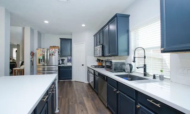 a kitchen with stainless steel appliances granite countertop sink stove refrigerator and cabinets