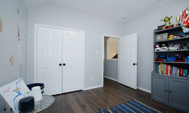 a view of room with baby crib and wooden floor