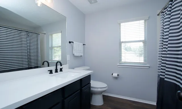 a bathroom with a double vanity sink toilet and a window