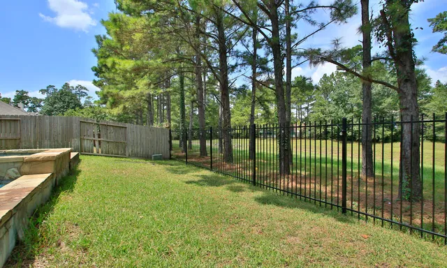 a view of a backyard with a fence and a large tree