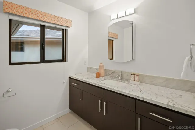 a bathroom with a granite countertop sink vanity and mirror