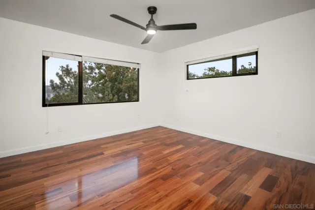 a view of empty room with wooden floor and fan