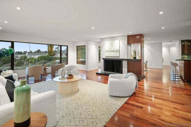 a living room with fireplace furniture and floor to ceiling windows