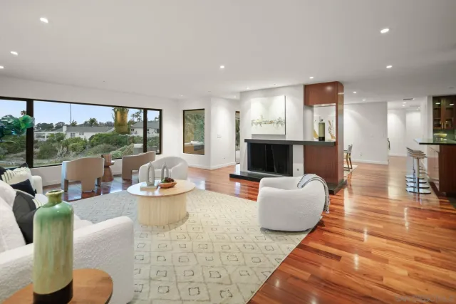 a living room with fireplace furniture and floor to ceiling windows