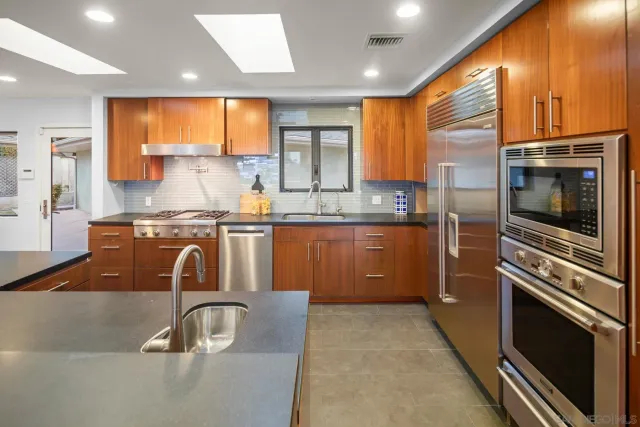 a kitchen with kitchen island granite countertop a stove a sink and dishwasher