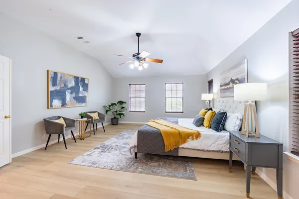 a bedroom with a bed ceiling fan and a wooden floor