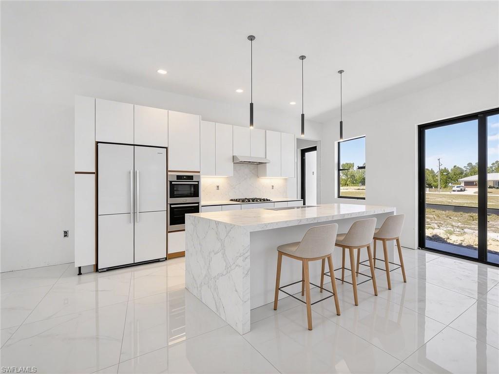 1213 Dodwin Street East Lehigh Acres, FL 33974 - Photo 6 of 28 a kitchen with stainless steel appliances granite countertop a refrigerator a stove a sink a dining table and chairs with wooden floor
