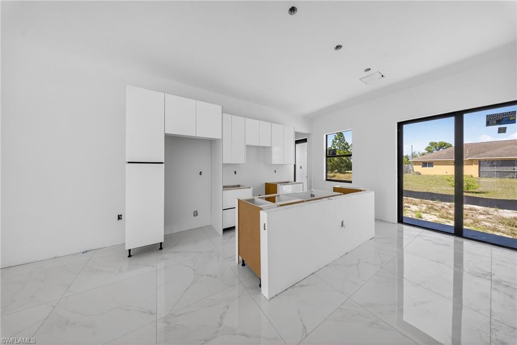 1213 Dodwin Street East Lehigh Acres, FL 33974 - Photo 9 of 28 a kitchen with granite countertop white cabinets and white appliances