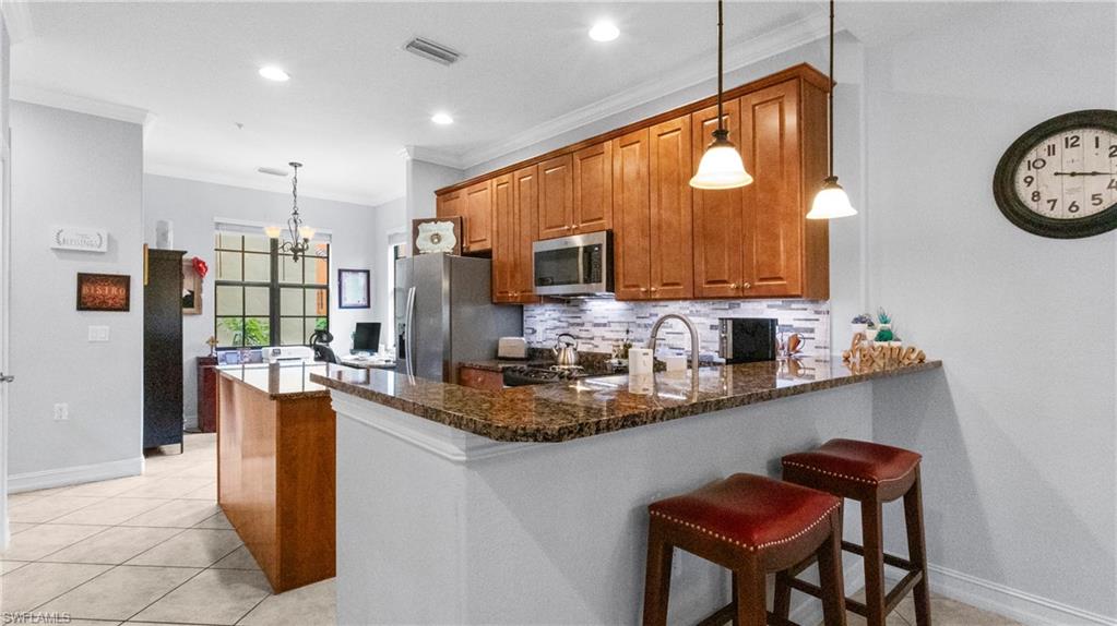 9080 Chula Vista Street, Unit 10401 Naples, FL 34113 - Photo 9 of 49 a kitchen with stainless steel appliances granite countertop a kitchen island a stove a sink a dining table and chairs