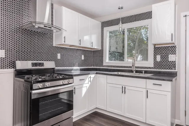 a kitchen with granite countertop a stove a sink and wooden floors